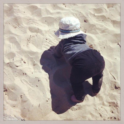Baby on the sand doing yoga.  